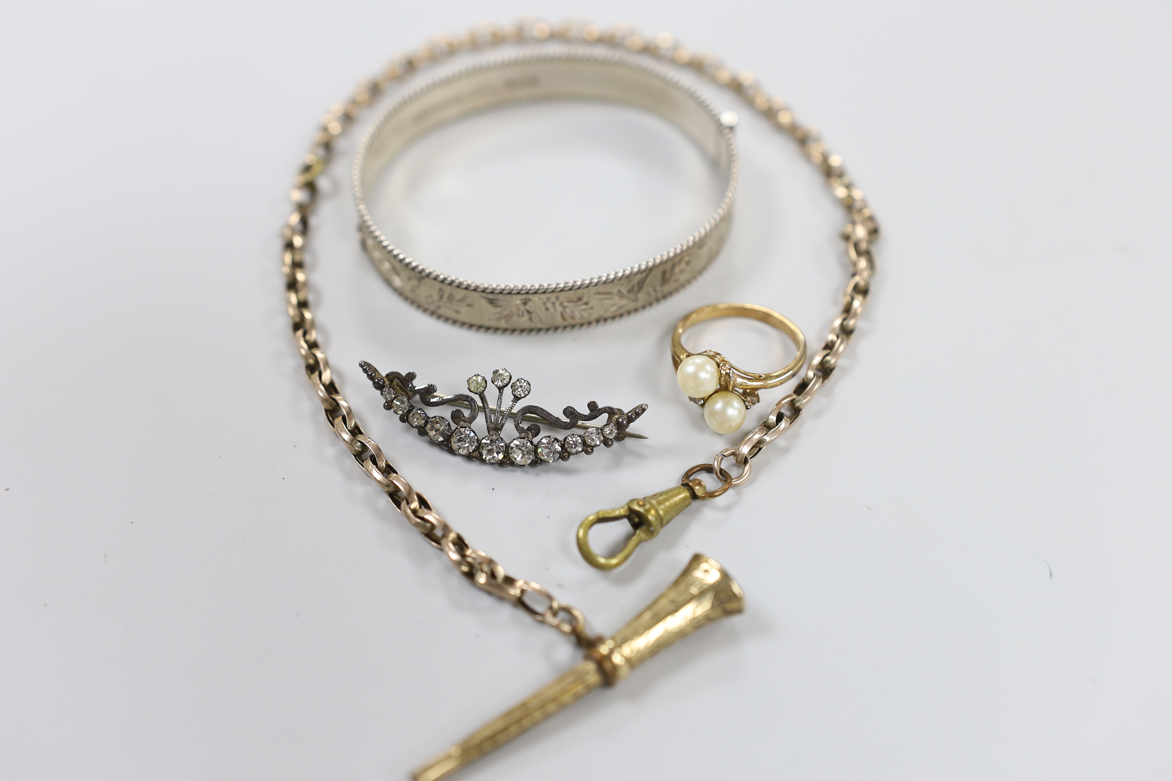 A silver hinged bangle and three other items including a paste set brooch.